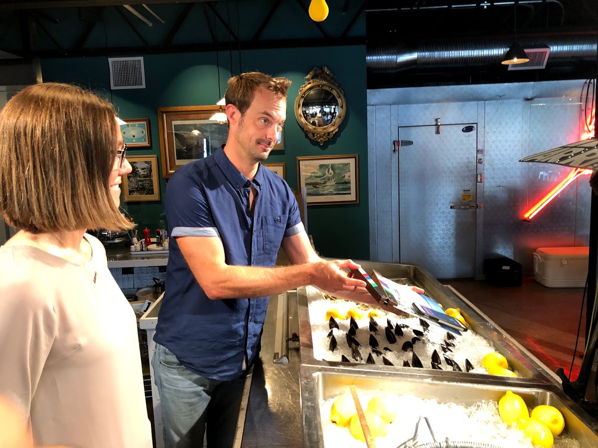 Chef Barton Seaver and Halley Froehlich stand behind a seafood counter full of mussels to demonstrate how to source them.