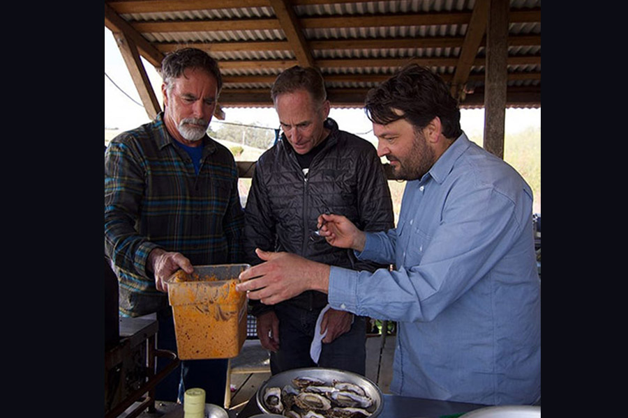 Chef Stuart Brioza and farmers Terry Sawyer and John Finger apply butter recipe to oysters before they grill them. 900x600 gallery.